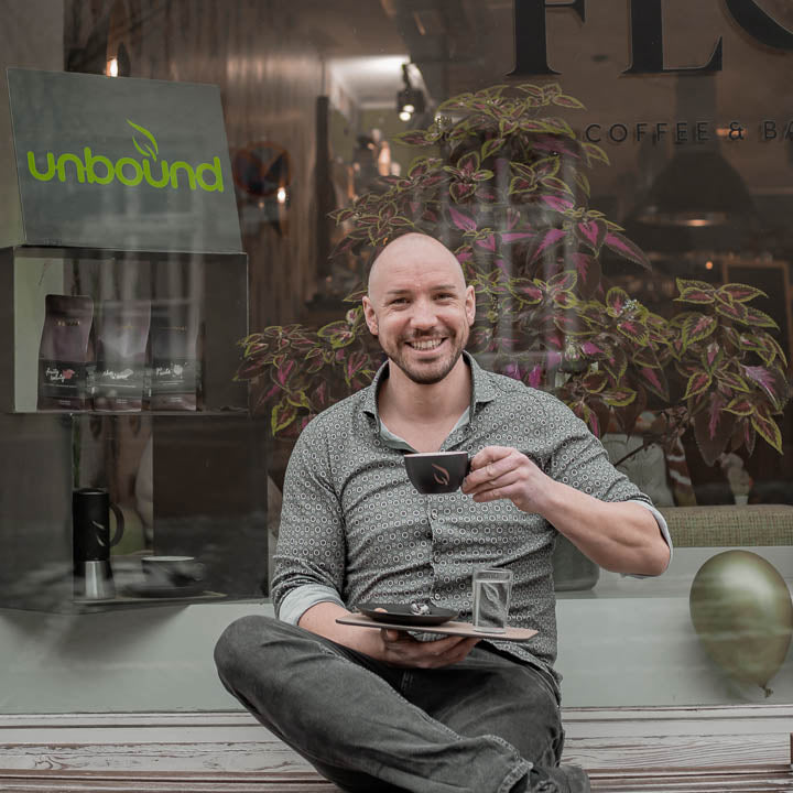 Florian trinkt unbound Kaffee vor dem Flos in Hall